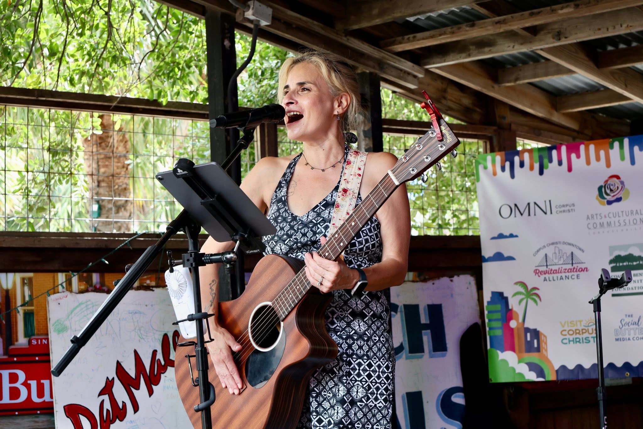 Lisa Sullivan on a stage playing a guitar, looking out into the crowd.